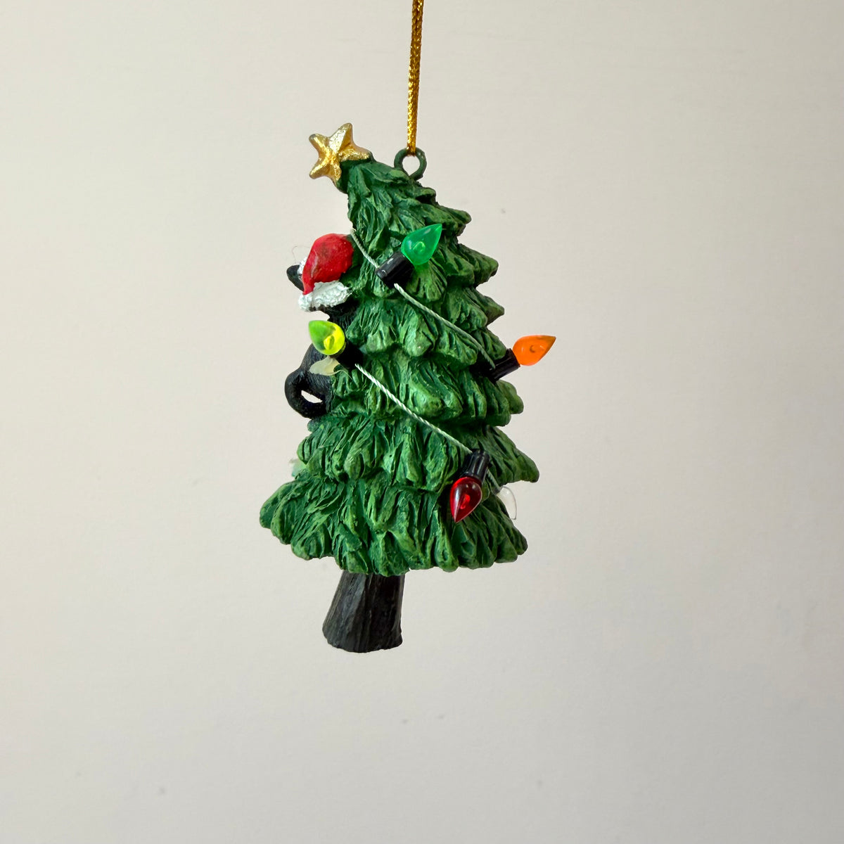Black Cat Knocking Down Tree Wrapped in Lights
