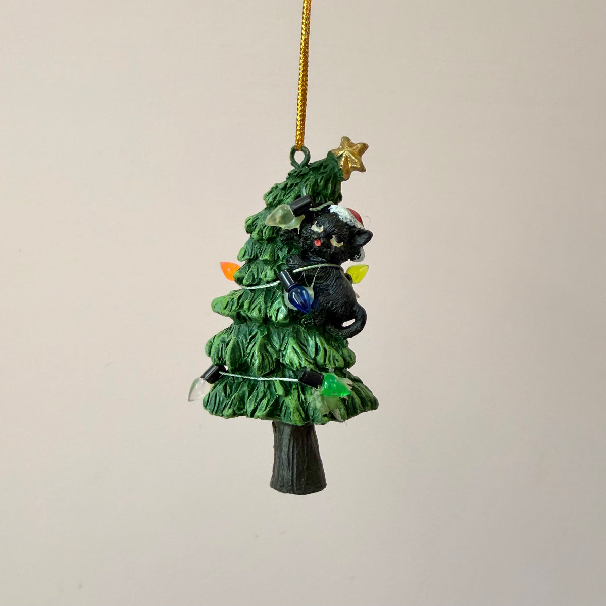 Black Cat Knocking Down Tree Wrapped in Lights